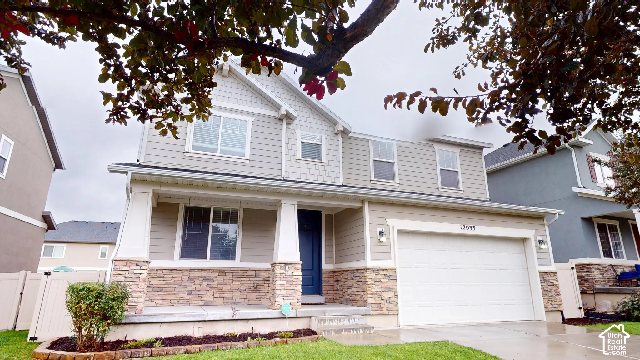 Two-story exterior featuring stone veneer accents, horizontal lap siding, a covered front porch with tapered columns, and an attached two-car garage