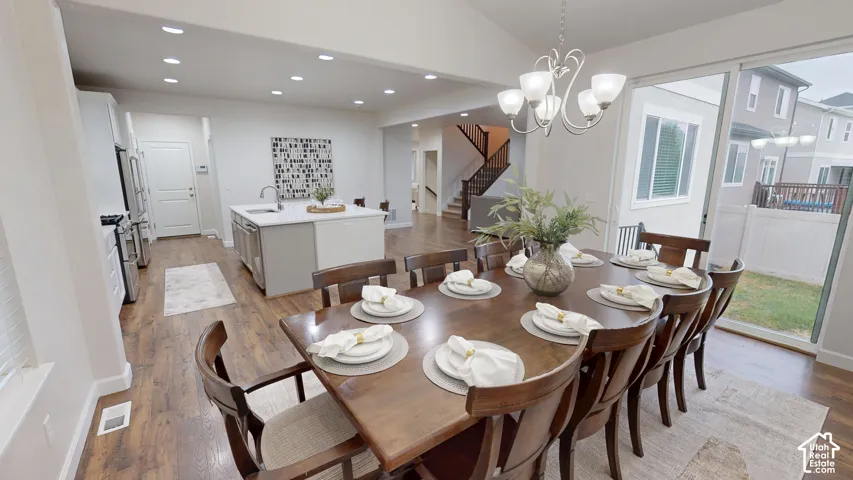 Open-concept kitchen featuring an island with a sink, recessed lighting, wood-finish flooring, and sliding glass doors to the exterior