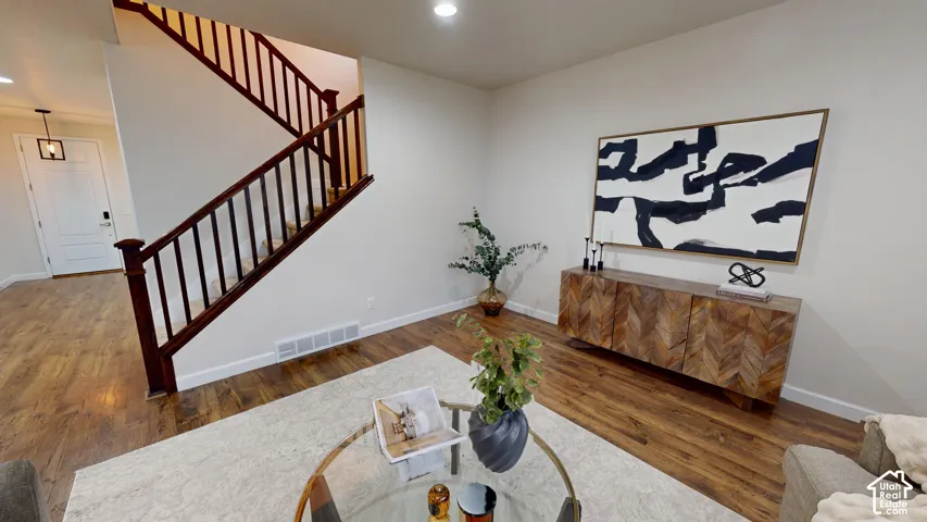 Open-concept space featuring wood-finish flooring, recessed lighting, and a staircase with a dark-stained wood railing and balusters
