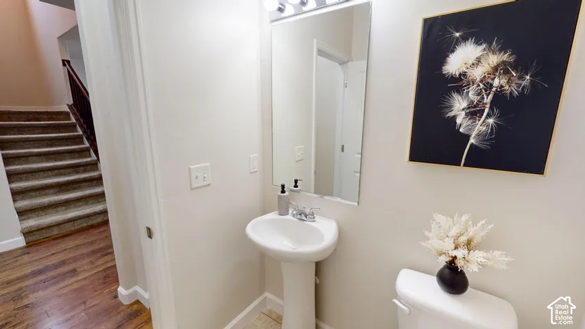Powder room featuring a white pedestal sink, polished chrome faucet, rectangular wall-mounted mirror, and tile flooring