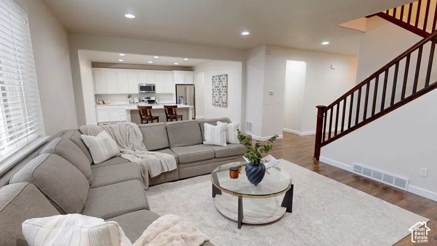 Open-concept interior featuring wood-finish flooring, recessed lighting, and white kitchen cabinetry with a central island