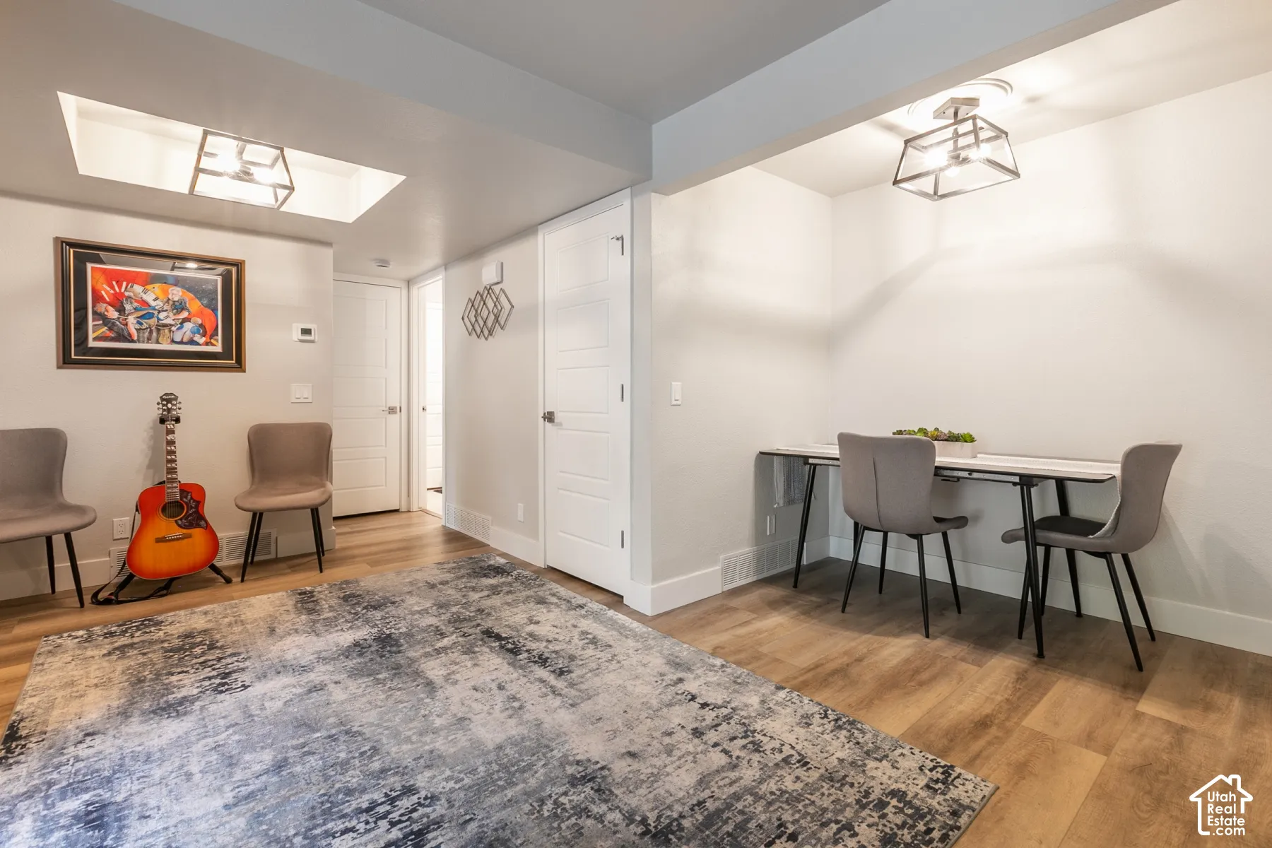 Wood-finish flooring throughout featuring dual recessed and geometric lantern-style pendant lighting, recessed ceiling architecture, and interior shaker-style doors