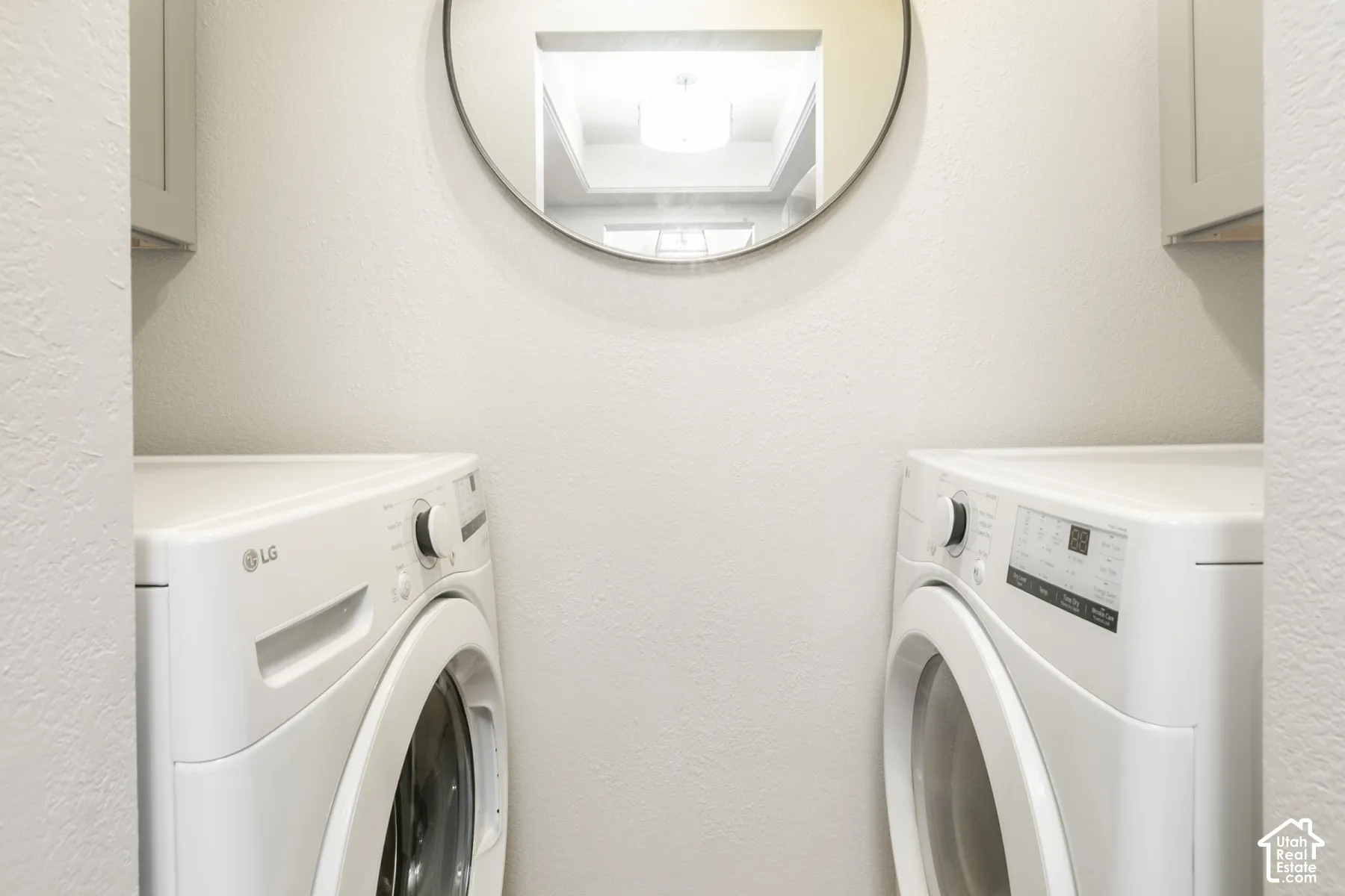 Built-in upper cabinetry, circular wall-mounted mirror, and neutral wall finish