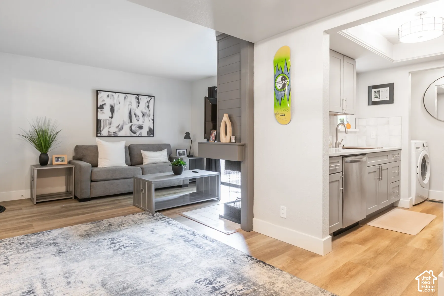 Open floor plan featuring wood-finish flooring, a double-sided fireplace with grey shiplap surround, stainless steel kitchen appliances, and shaker-style cabinetry