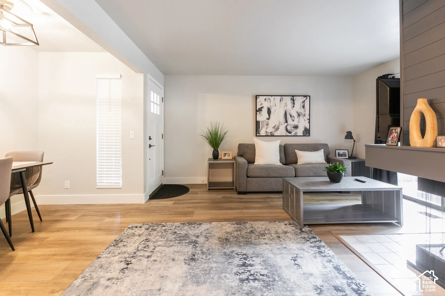 Living area featuring wood-finish flooring, a fireplace with a wood-plank surround, and a geometric pendant light fixture