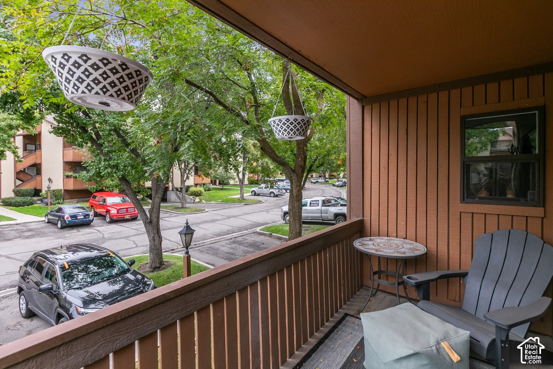 Covered balcony featuring vertical wood siding, a wooden railing, and a window