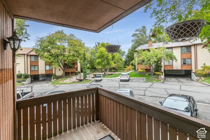 Covered exterior balcony featuring wood-slat railing and wall-mounted light fixture