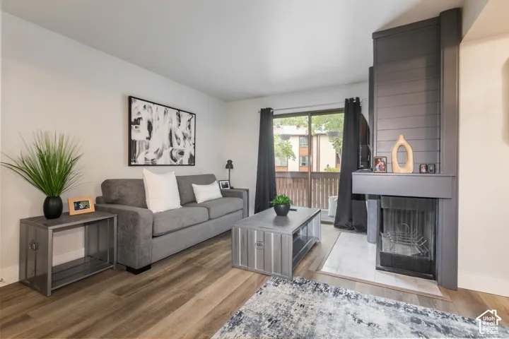Wood-finish flooring, floor-to-ceiling shiplap fireplace surround, and glass sliding door access to a balcony