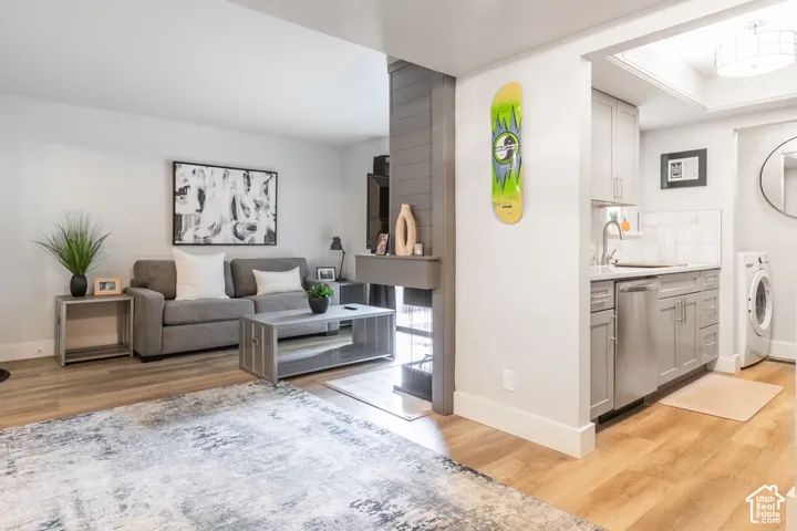 Open floor plan featuring wood-finish flooring, a double-sided fireplace with grey shiplap surround, stainless steel kitchen appliances, and shaker-style cabinetry