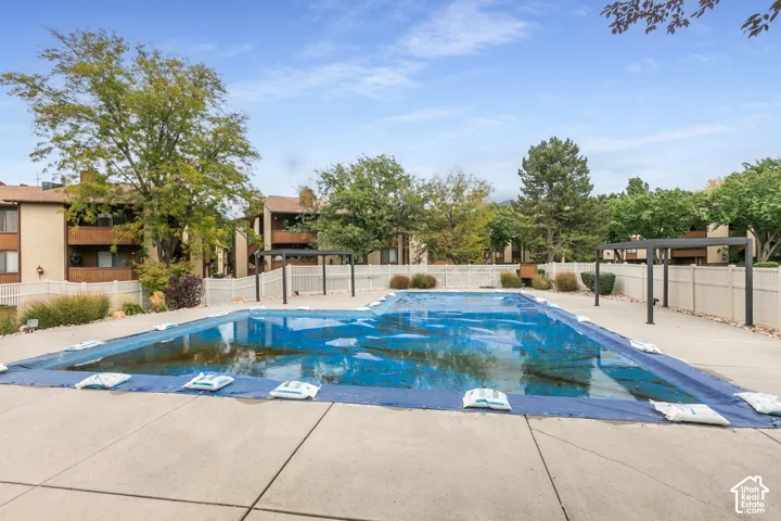 Swimming pool with concrete decking, perimeter vinyl fencing, and metal shade structures