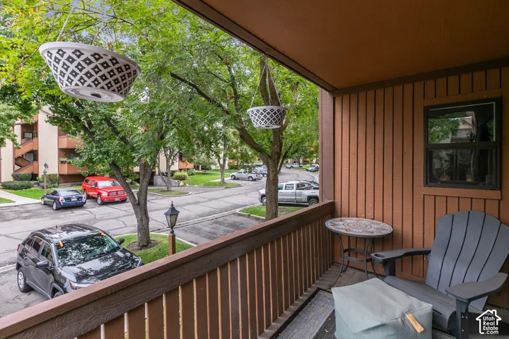 Covered balcony featuring vertical wood siding, a wooden railing, and a window