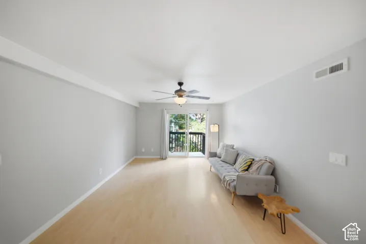 Bright living area with light wood-finish flooring, crisp white baseboards, and crown molding