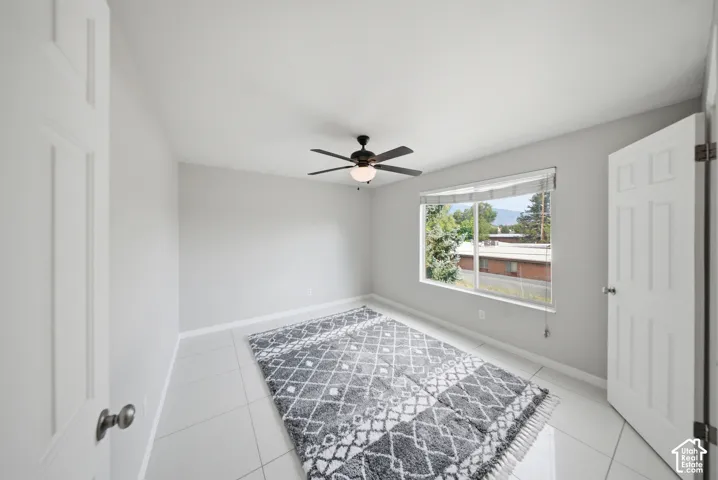 Large primary bedroom  ceiling fan with integrated lighting, and white tile flooring
