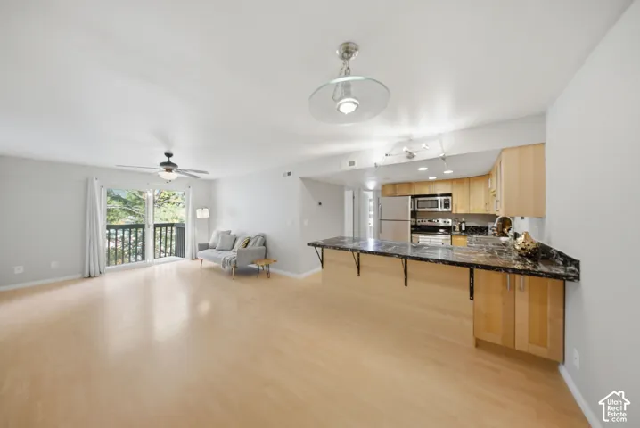Open-concept living space featuring wood-finish flooring, a contemporary ceiling fan, and a sliding glass door opening to a private balcony