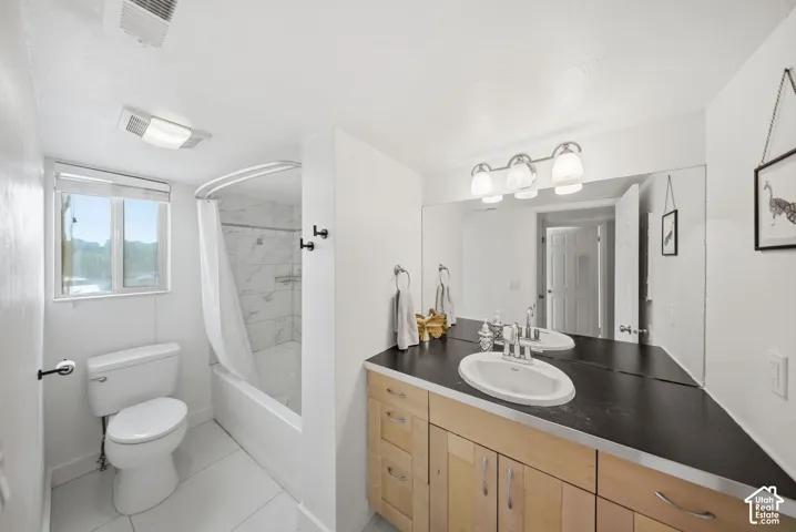 Bathroom featuring a wood-finish vanity with a dark countertop and integrated sink, a large wall-mounted mirror, and a three-light vanity fixture