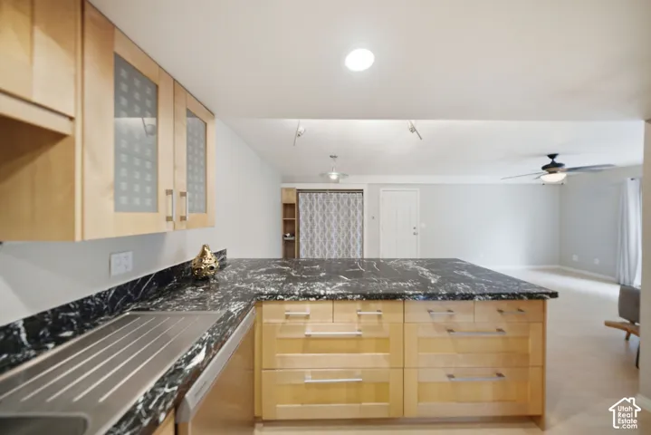 Kitchen island with black stone countertop and light wood cabinetry