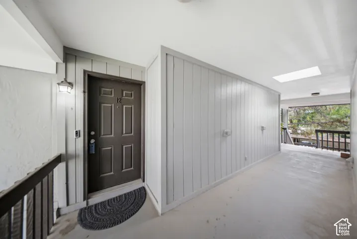 Entryway featuring a six-panel door, vertical plank wall paneling, and a skylight