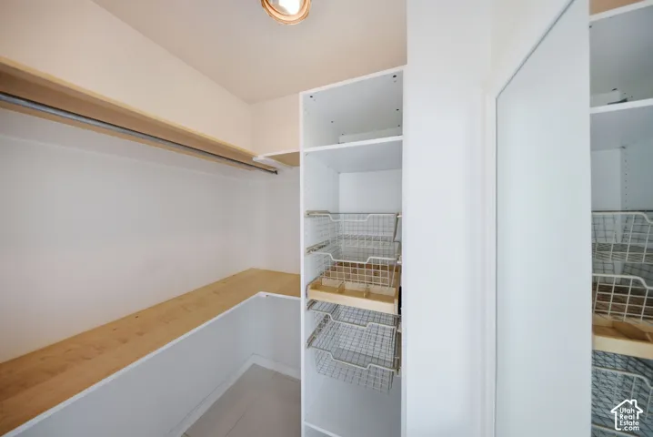 Walk-in closet featuring built-in shelving, hanging rods, and integrated wire basket drawers