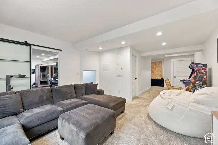 Neutral-toned interior space featuring recessed ceiling lighting, wall-to-wall carpeting, and a frosted glass sliding barn door with a matte black hardware track