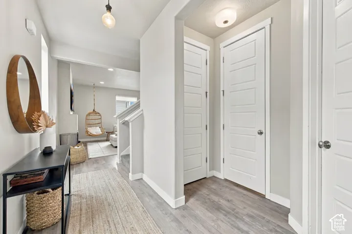 Hallway featuring wood-finish flooring, five-panel interior doors, and modern light fixtures