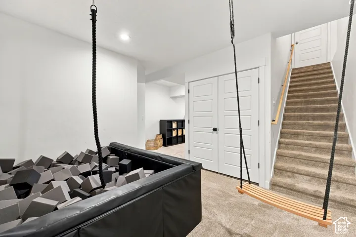 Interior space featuring recessed lighting, carpeting, double doors with matte black hardware, and an integrated staircase with a wooden handrail