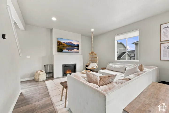 Fireplace with a minimalist surround, recessed lighting, and wood-finish flooring