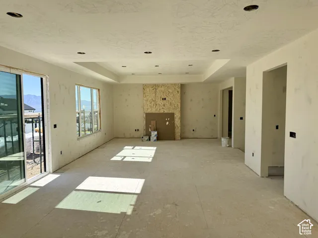 Open-concept interior featuring a recessed tray ceiling, a central rock fireplace surround, and sliding glass doors with mountain scenery