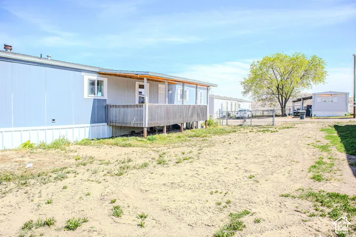 Exterior view featuring vertical panel siding, a covered wooden deck with railing, and a fenced yard