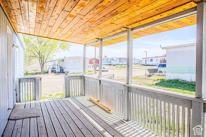 Covered exterior porch featuring a wood-plank ceiling, plank flooring, and painted railings