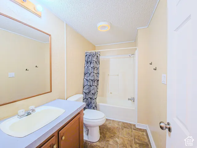 Full bathroom featuring a wood-finish vanity with an integrated oval sink, large wall-mounted mirror, combination tub and shower unit, and patterned flooring