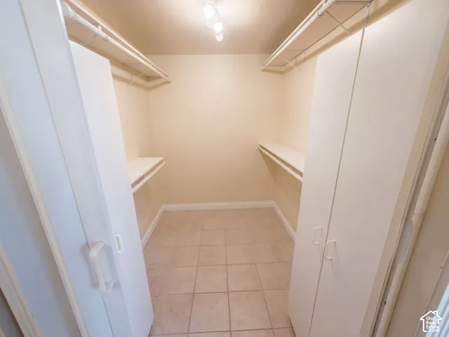 Walk-in closet featuring ceramic tile flooring, built-in cabinetry, and dual-tier hanging storage racks