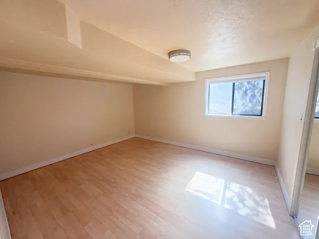 Room featuring wood-finish flooring, a sloped ceiling, and a flush-mount ceiling light fixture