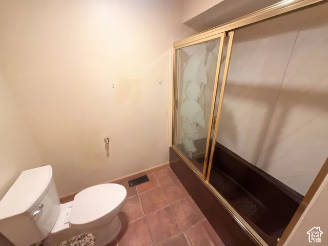 Bathroom featuring ceramic tile flooring, a tub-shower combination with etched glass sliding doors, and neutral-toned wall surfaces