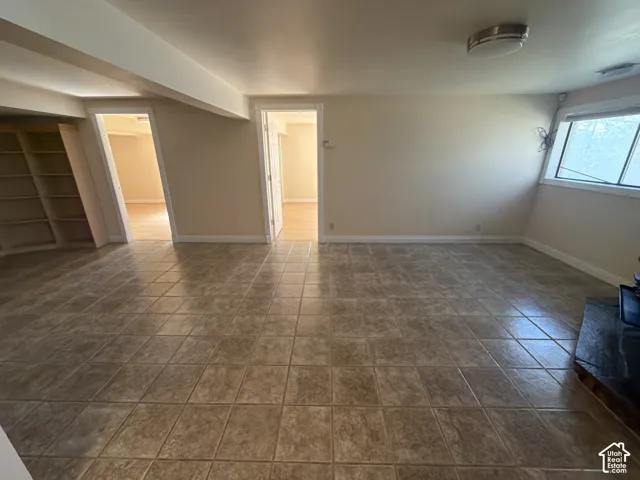 Interior space featuring square tile flooring, built-in recessed shelving, a stone-surround hearth, and flush-mount lighting