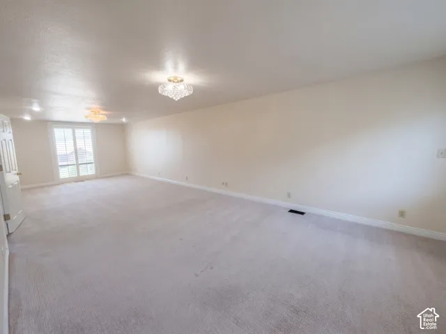 Spacious room featuring wall-to-wall carpeting, recessed lighting, decorative ceiling fixtures, and glass-paned double doors