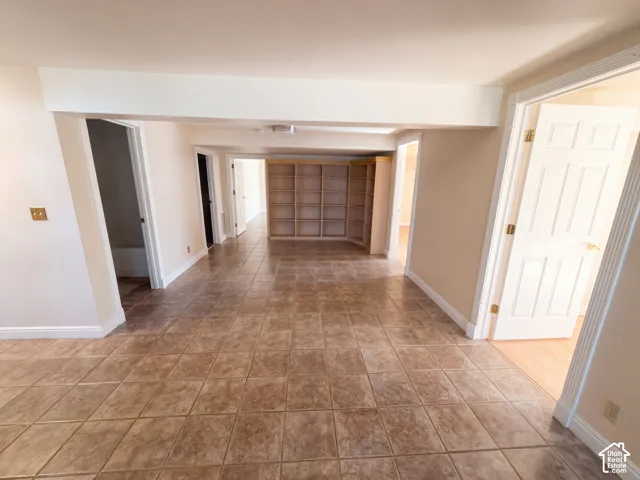 Neutral-toned interior space featuring ceramic tile flooring, custom built-in wood shelving, and multi-panel interior doors