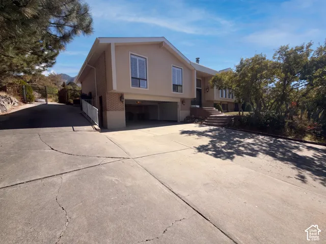 Split-level exterior featuring brick and stucco siding, a built-in two-car garage, and concrete driveway