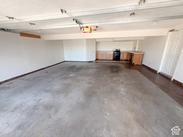 Garage workspace featuring concrete flooring, built-in wooden cabinetry, a range, and a sink