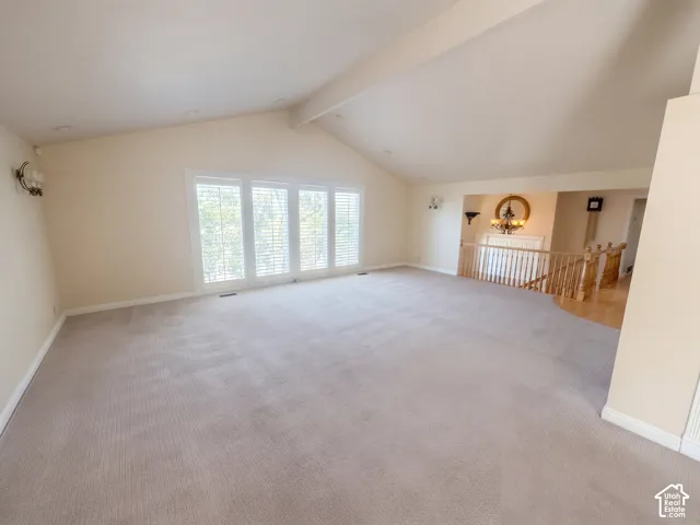 Vaulted ceilings, large windows with shutters, wall-mounted light fixtures, and wooden stair railings