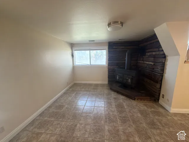Tile flooring, natural stone accent wall, and wood-burning stove on a raised hearth