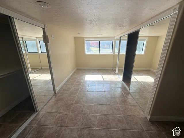 Room featuring tile flooring, recessed lighting, and dual mirrored sliding-door closets