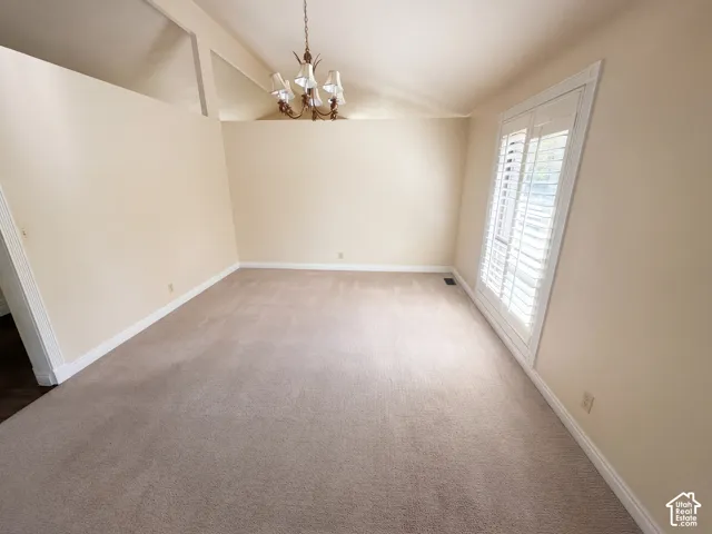 Vaulted ceiling with transom windows, neutral wall-to-wall carpeting, and plantation shutters