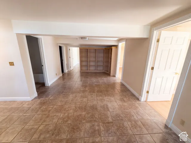 Ceramic tile flooring throughout with built-in wooden shelving and multiple paneled doors