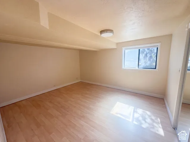 Room featuring light-toned wood-finish flooring, a neutral color palette, and a flush-mount circular ceiling light fixture