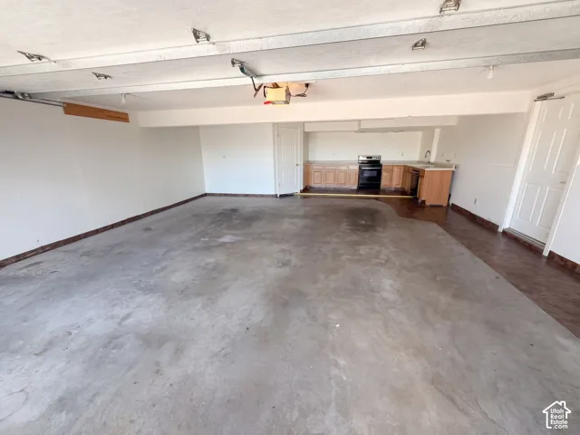 Multi-car garage featuring concrete flooring, built-in cabinetry, an integrated stove, and a sink