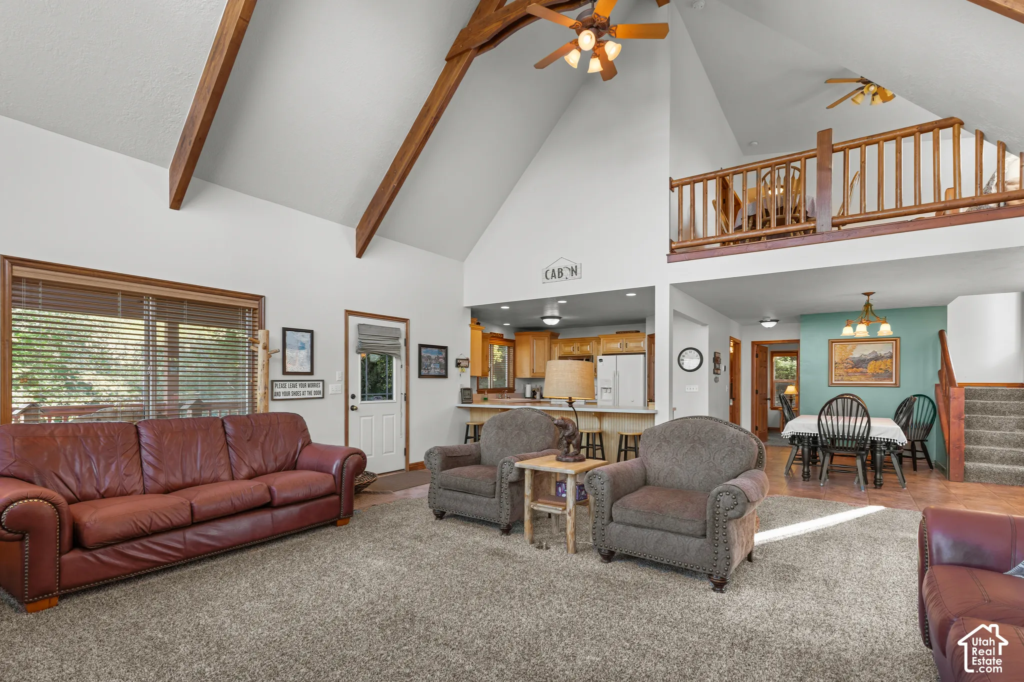 Vaulted ceilings featuring exposed timber beams, a mezzanine loft with a wooden balustrade, and a breakfast bar