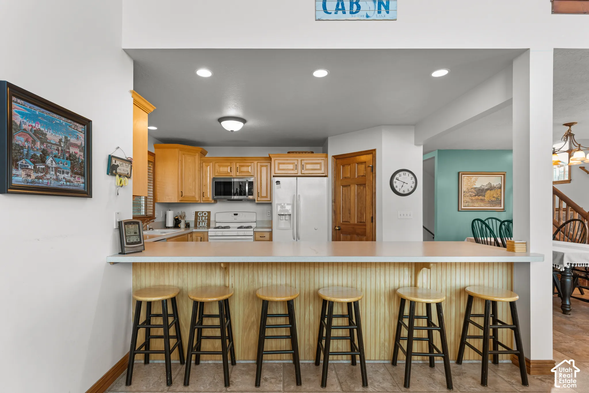 Kitchen featuring wood cabinetry, solid-surface breakfast bar, recessed lighting, and tile flooring