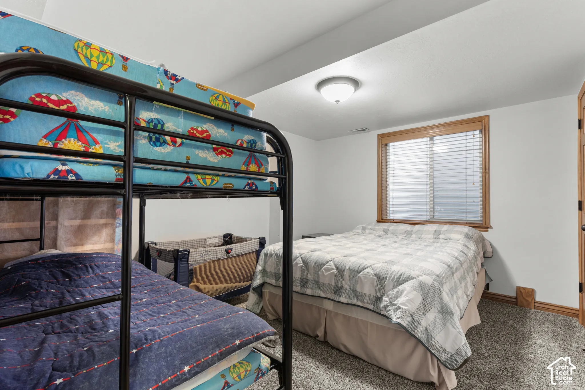 Neutral-toned wall paint, wall-to-wall carpeting, window with wood-trim casing, horizontal slat blinds, and flush-mount ceiling light fixture