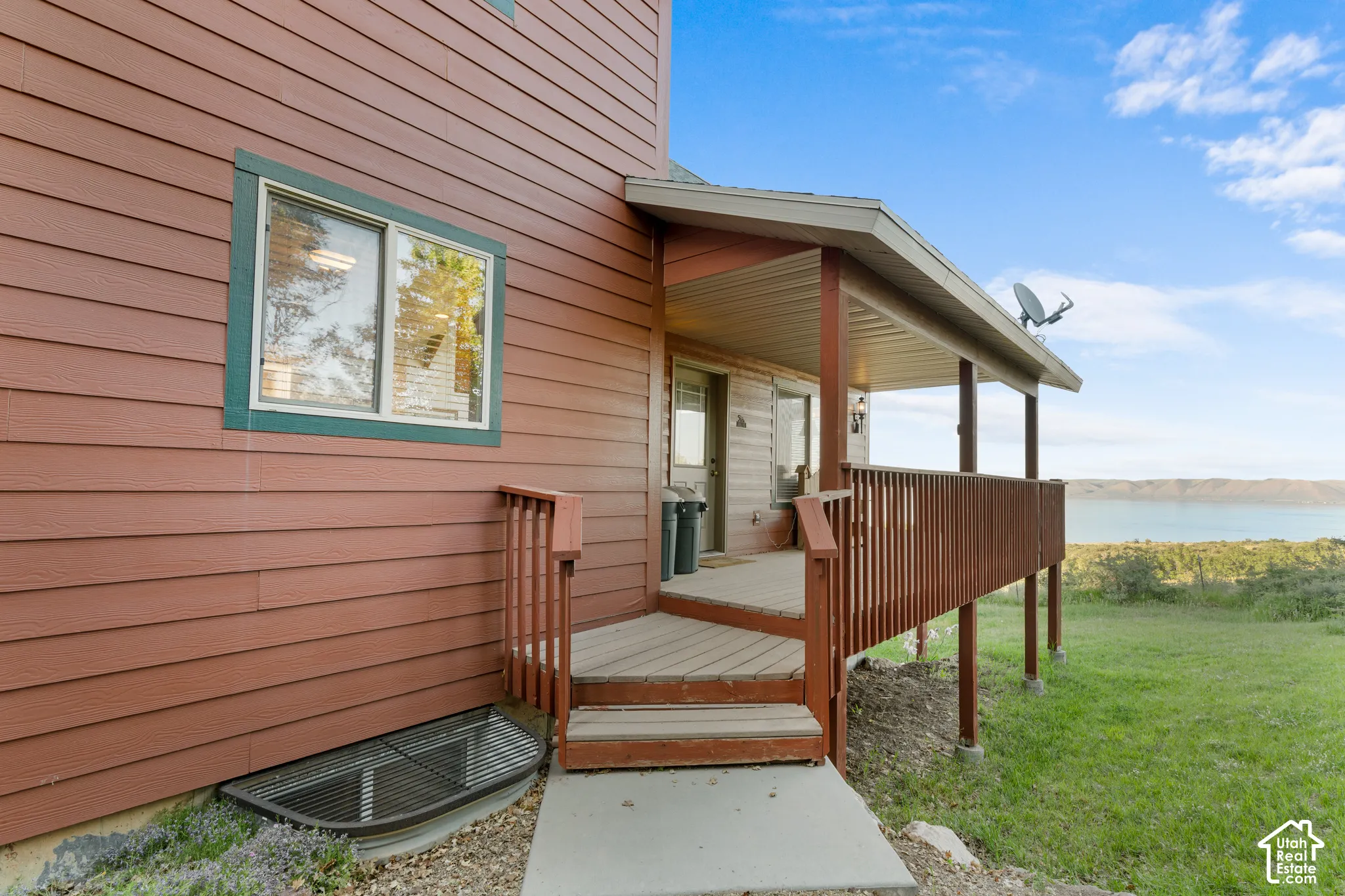 Exterior featuring horizontal lap siding, a covered deck with wooden railings, and a concrete entrance path