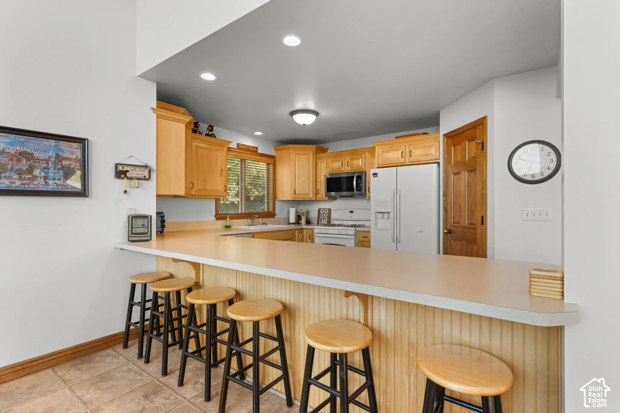 Kitchen featuring wood cabinetry, solid-surface breakfast bar, recessed lighting, tile flooring, and built-in microwave
